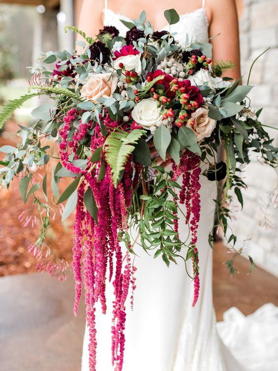 a lush and bold wedding bouquet of white and blush roses, berries of various kinds, greenery and amaranthus is wow