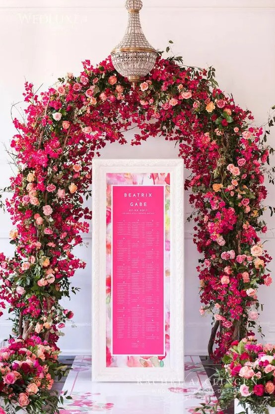 a lush and colorful wedding arch with pink, hot pink and fuchsia blooms plus greenery is wow