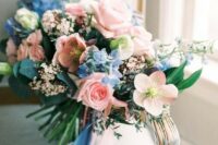 a lush pastel wedding bouquet in light blue and pink with matching ribbons hanging down