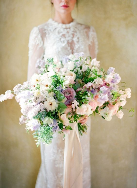 a lush pastel wedding bouquet of blush, lilac and neutral blooms, lilac sweet peas, lilac blooming branches and greenery is amazing for spring
