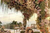 a lush summer wedding arch covered with blush, pink, white and peachy roses, green amaranthus, twigs and greenery is a chic and cool idea