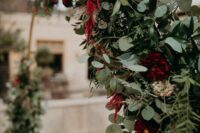 a lush textural wedding arch with lots of various greenery, blush blooms, amaranthus is a cool solution for a fall wedding