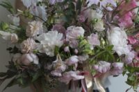 a lush wedding bouquet of various types of blooms in blush and pink shades including sweet peas and peonies is amazing