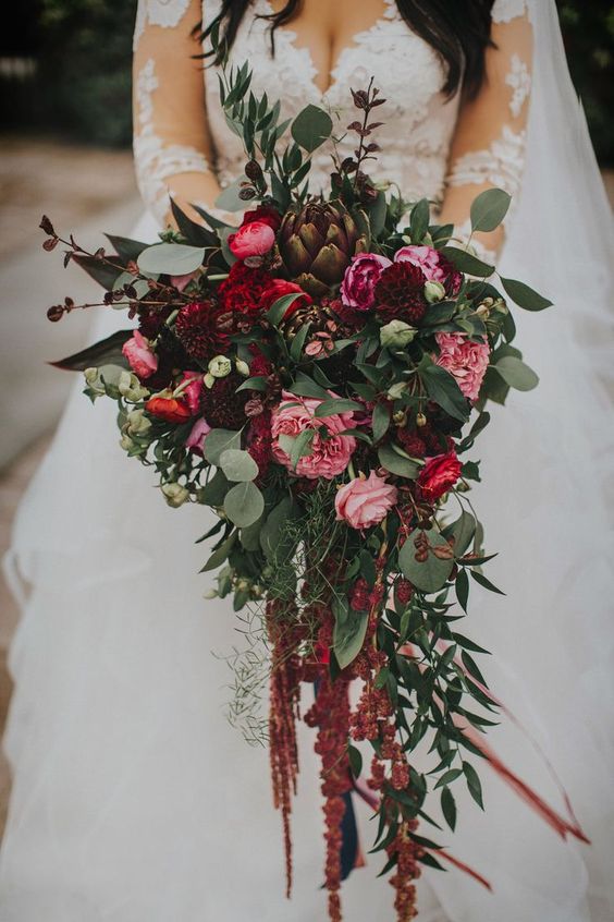 a luxurious wedding bouquet of pink and burgundy blooms, greenery, an artichokes, berries and amaranthus is bold and cool