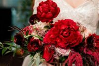 a luxurious wedding bouquet of red and pink roses and red peonies, greenery and amaranthus plus long ribbon