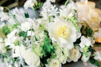 a luxurious white wedding centerpiece of peonies, roses, sweet peas and some greenery is amazing