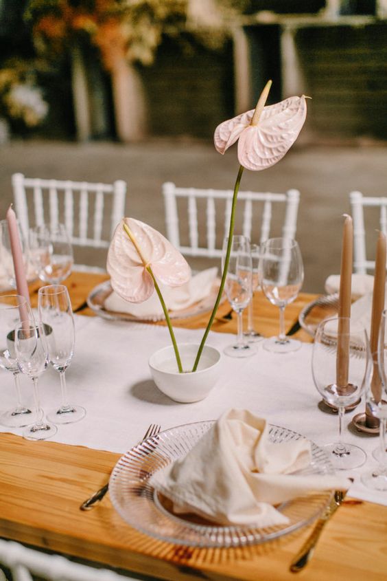 a minimalist wedding centerpiece of blush anthuriums and blush candles is a cool idea for a modern or minimal wedding