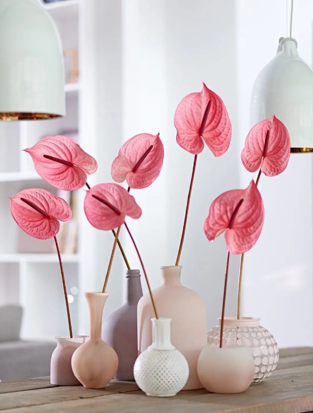 a modern wedding centerpiece of mismatching matte vases and pink anthurium is a stylish and bold idea