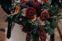 a moody wedding bouquet of burgundy and peachy blooms, greenery, thistles, berries and amaranthus for a boho fall wedding