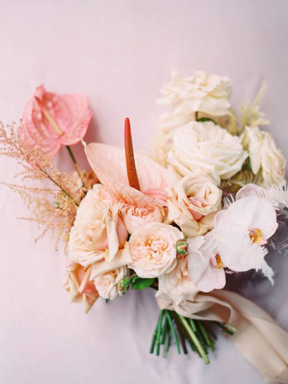 a neutral wedding bouquet of blush roses and carnations, orchids and peonies and anthurium and grasses