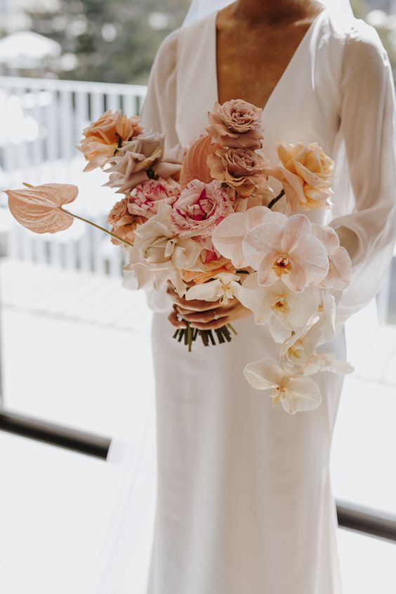 a neutral wedding bouquet of white and blush orchids, blush and white roses plus coffee-colored ones and some anthurium