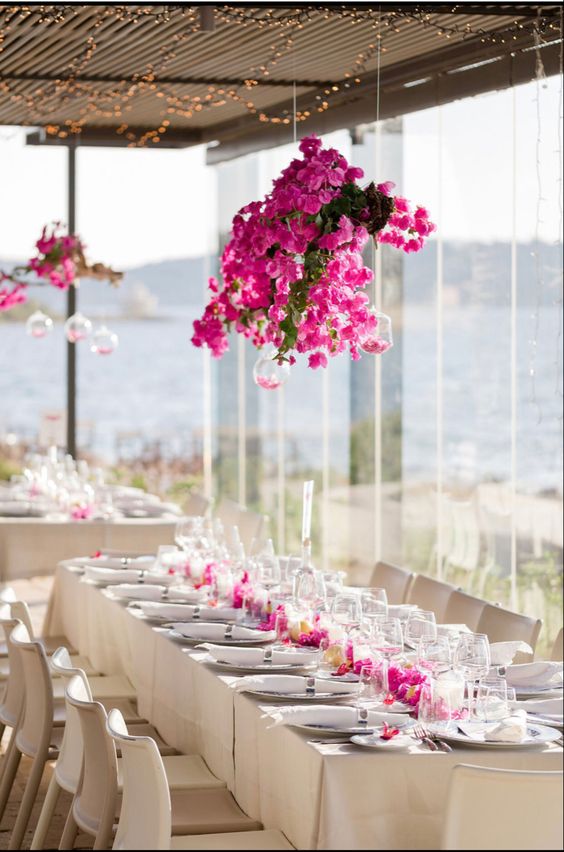 a overhead wedding installation of greenery and bougainvillea plus some bubbles with petals is a stunning solution for a modern wedding