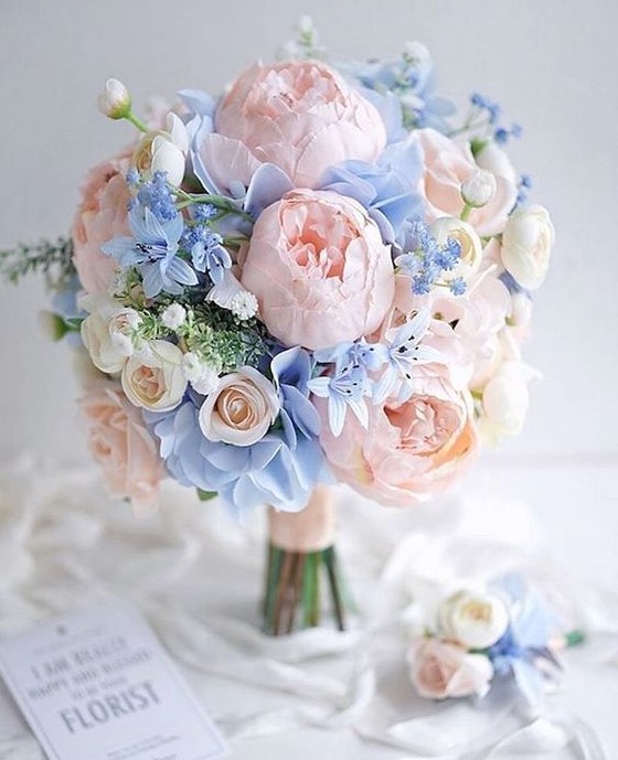 a pastel wedding bouquet in blush and pastel blue plus greenery and some neutral blooms
