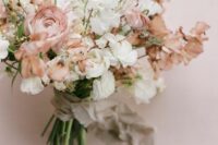 a pastel wedding bouquet of white and dusty pink sweet peas and dusty pink ranunculus plus long ribbon