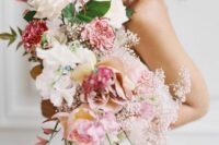 a pink cascading wedding bouquet of coffee-colored and white roses, pink carnations, pink sweet peas, some fillers and bold leaves