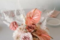 a pink wedding centerpiece of pale pink roses, dahlias and ranunculus, anthurium, white leaves is a lovely idea