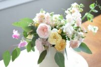 a pretty spring wedding centerpiece of blush and yellow peony roses, blush sweet peas, greenery is a cool solution