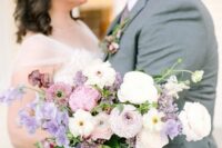 a pretty wedding bouquet of white, pink and mauve blooms with ranunculus and sweet peas and greenery is chic for spring