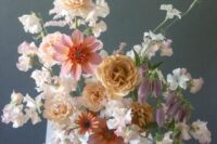 a refined and delicate wedding centerpiece of neutral sweet peas and pink and rust blooms is a lovely idea for spring
