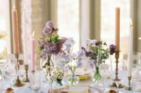 a refined cluster wedding centerpiece of purple and lilac sweet peas, lilac and chamomiles and candles around is amazing