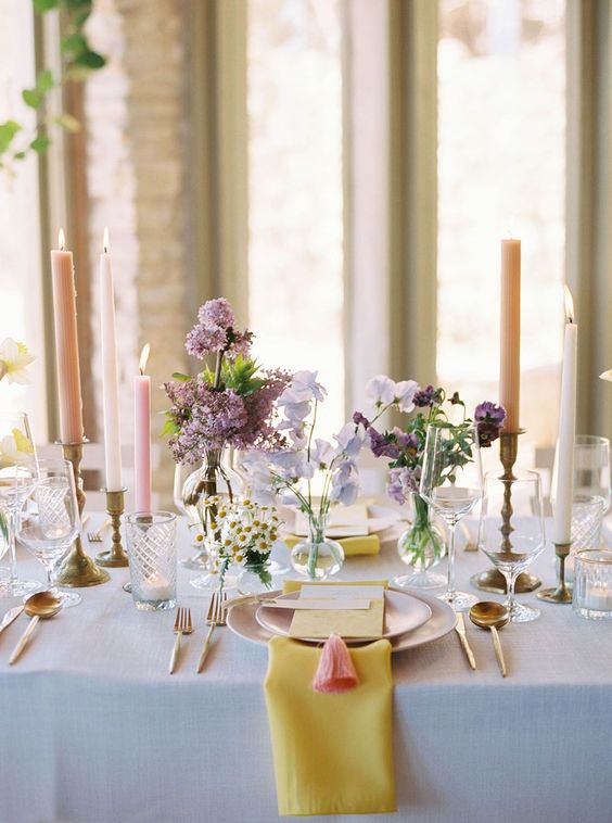 a refined cluster wedding centerpiece of purple and lilac sweet peas, lilac and chamomiles and candles around is amazing
