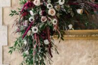 a refined fall wedding arch done with white, blush roses, deep purple ones, white anemones, greenery and amaranthus