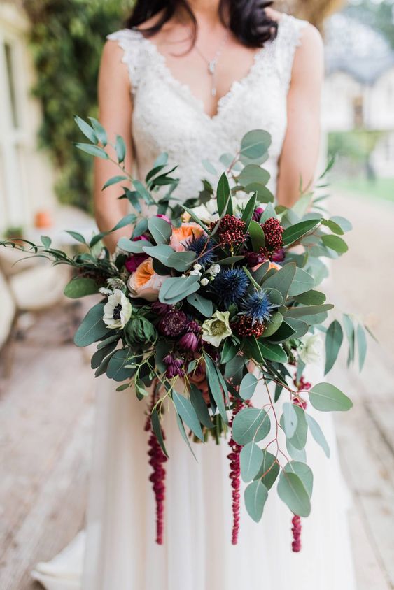 a refined fall wedding bouquet of blush peony roses, burgundy blooms, blue thistles, greenery and amaranthus is wow