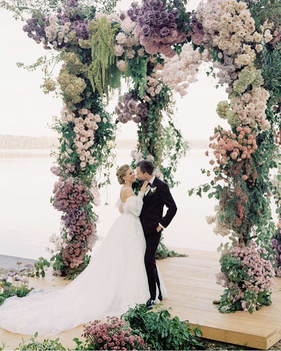 a romantic pastel wedding arch with greenery, blush, lilac and purple blooms and green amaranthus is a lovely and delicate solution