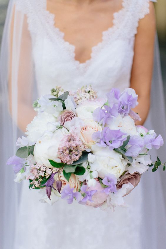 a romantic wedding bouquet of white roses and blush and mauve ones, lilac sweet peas, pink fillers for a spring or summer wedding