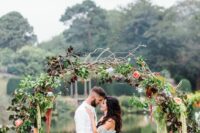 a round wedding arch of greenery, dark foliage, twigs and branches, deep purple dahlias and amaranthus is amazing for the fall