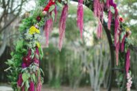 a round wedding arch with greenery, red, fuchsia and burgundy blooms and amaranthus is a catchy idea for a fall wedding