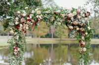 a rustic wedding arch done with greenery, blush, white and burgundy roses and dahlias, hydrangeas and amaranthus