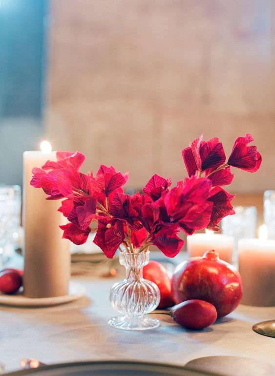 a simple and bold wedding centerpiece of bougainvillea in a glass vase and pillar candles around for a Mediterranean wedding