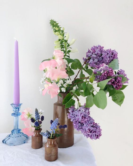 a simple and catchy wedding centerpiece of pink sweet peas and lilac, greenery and some bulbs plus a lilac candle is cool