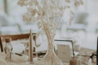 a simple and lovely bleached wedding centerpiece of lunaria and bunny tails plus candles around is a cool idea for a boho wedding
