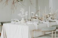 a simple lunaria wedding centerpiec eof a white vase and blooms and white rose centerpieces with bloomign branches look lovely