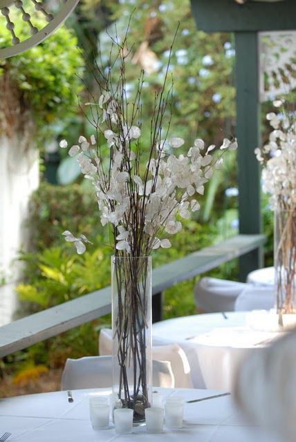 a simple lunaria wedding centerpiece of a clear vase, branches and lunaria is a cool and modern idea for a wedding, and you can arrange one yourself