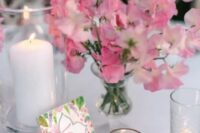 a simple wedding centerpiece of pink sweet peas and candles around is a lovely idea for a pink-infused wedding