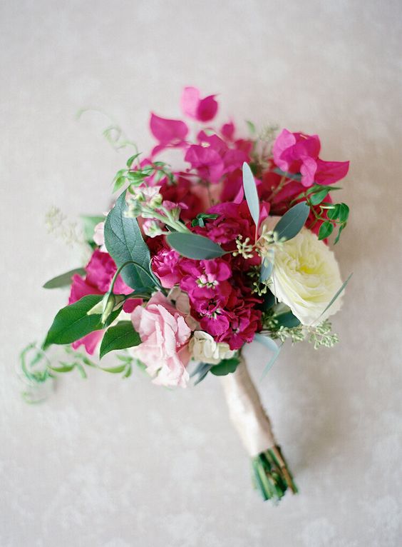a small and lovely wedding bouquet of a white and pink rose, bougainvillea and greenery is a fun and cool idea for a summer wedding
