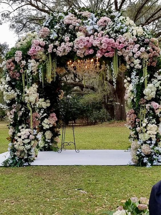 a sophisticated wedding arch covered with greenery, white and pink roses and green amaranthus is adorable for a garden wedding