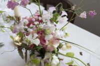 a spring or summer wedding centerpiece of pink and white blooms including sweet peas and fruits on the table is amazing