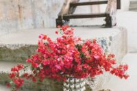 a stunning bougainvillea wedding centerpiece of a glass vase and blooming branches is a cool idea for a Mediterranean wedding