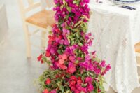 a stunning descending wedding table runner of bougainvillea and greenery is a beautiful alternative to a usual centerpiece