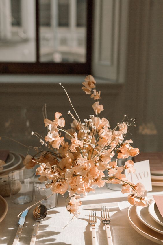 a stylish modern wedding centerpiece of peachy-colored sweet peas and some fillers is a lovely idea for spring or summer