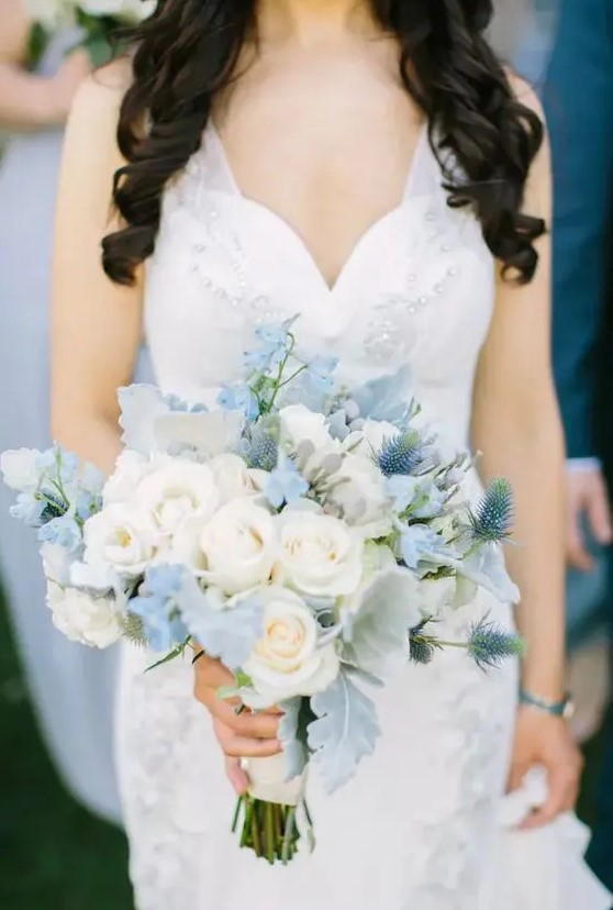 a subtle wedding bouquet of white roses, serenity blue sweet peas, pale foliage and thistles is a chic and stylish idea