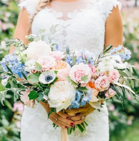 a super lush and dimensional wedding bouquet made of blue blooms, light pink roses, white peony roses and anemones plus lots of greenery