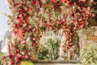 a super lush and jaw-dropping wedding arch with light pink and pink blooms, burgundy roses, white anemones, greenery and pampas grass