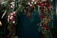 a super lush and moody wedding arch with greenery, blush, fuchsia, burgundy blooms, foliage, pampas grass and amaranthus for a fall boho wedding