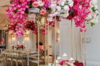 a tall wedding centerpiece on gilded stands, with white, light pink, hot pink blooms and greenery for a luxurious wedding
