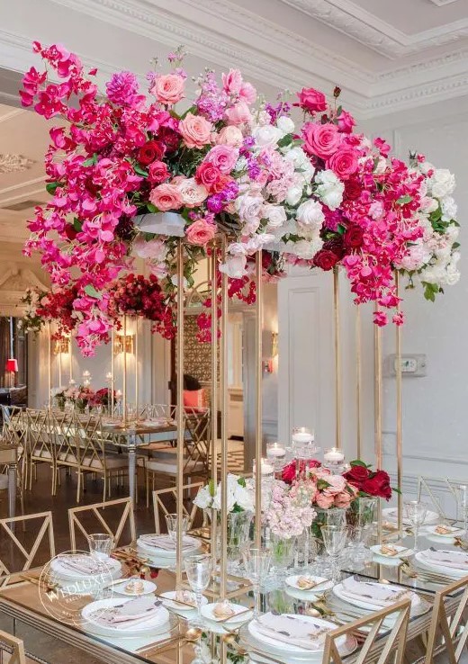 a tall wedding centerpiece on gilded stands, with white, light pink, hot pink blooms and greenery for a luxurious wedding